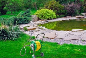 Garden Hose Reel in Yard Near Pond