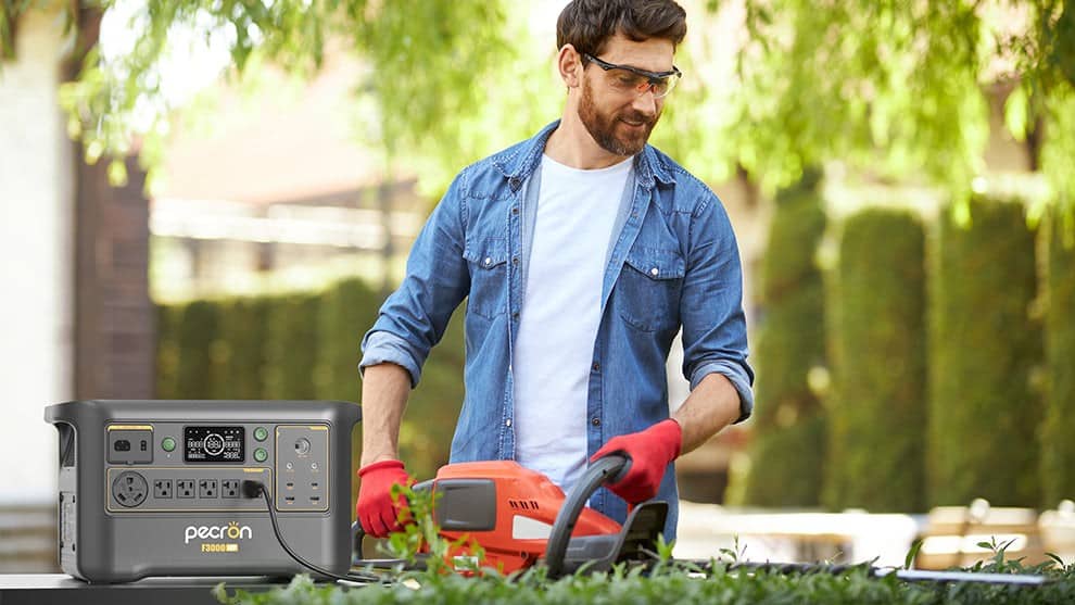 Pecron F3000LFP portable power station powering an electric hedge trimmer in the yard